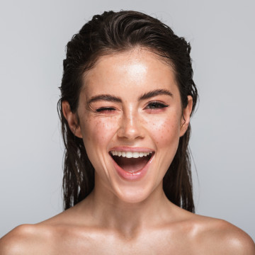 Jungen geschminkte Frau die Augenlid zudrückt und lacht